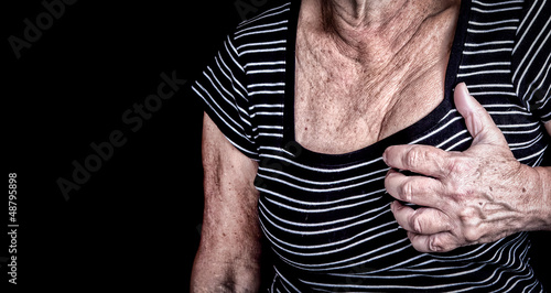 Photo: Woman suffering from chest pain isolated on black Woman suffering from chest pain isolated on black