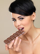 Woman biting into a bar of chocolate