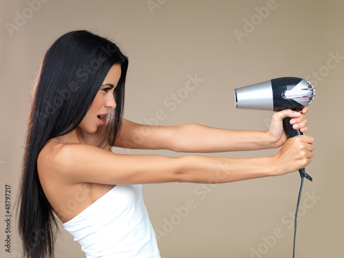 Photo: Playful woman having fun with a hairdryer Playful woman having fun with a hairdryer