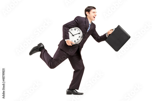 Photo: Full length portrait of a businessman running with clock and bri Full length portrait of a businessman running with clock and bri