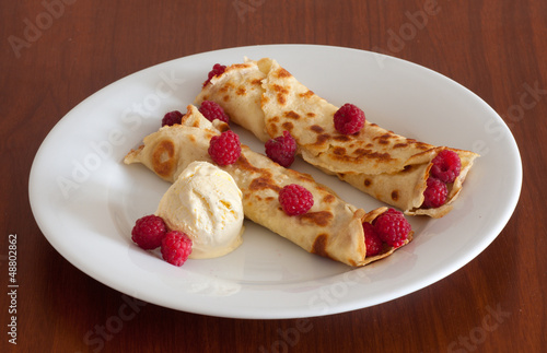 Photo: Crepes with raspberries and vanilla ice cream on a white plate Crepes with raspberries and vanilla ice cream on a white plate