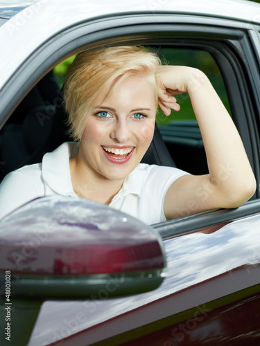 Photo: Beautiful young woman beaming with joy in her new car Beautiful young woman beaming with joy in her new car