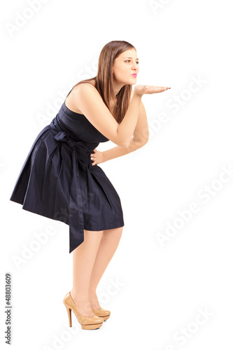 Photo: Full length portrait of a young woman blowing a kiss Full length portrait of a young woman blowing a kiss