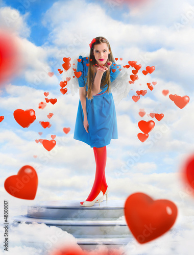 Photo: Beautiful angel woman blowing red hearts from the sky Beautiful angel woman blowing red hearts from the sky