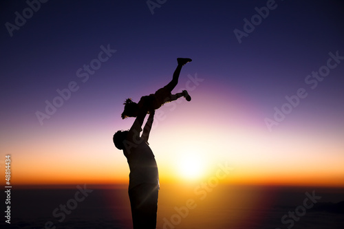 Photo: The silhouette of happy father and little girl with sunrise back The silhouette of happy father and little girl with sunrise back