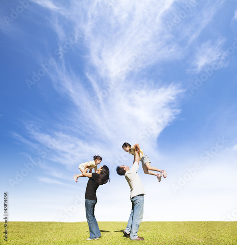 Photo: happy family on the grass with cloud background happy family on the grass with cloud background
