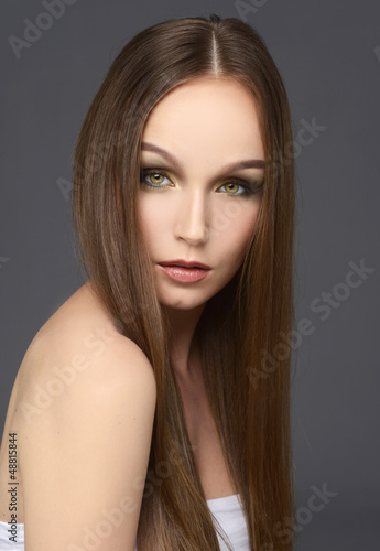 Photo: Attractive girl with long hair on gray Attractive girl with long hair on gray