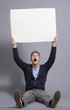 Photo: Astonished young man holding up empty panel. Astonished young man holding up empty panel.