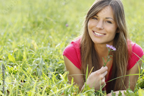 Photo: Glückliche Frau hält eine lila Blume in der Wiese Glückliche Frau hält eine lila Blume in der Wiese