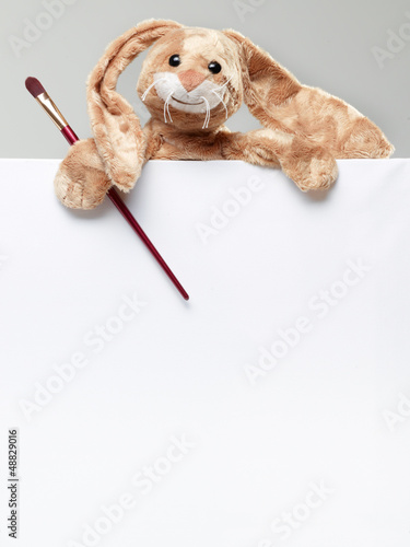 Photo: Stuffed bunny peeking behind blank board Stuffed bunny peeking behind blank board
