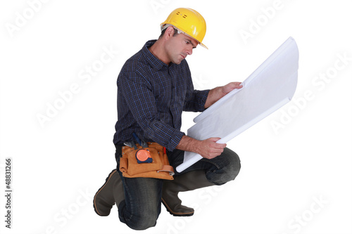 Photo: Frowning tradesman examining a blueprint Frowning tradesman examining a blueprint