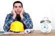 Construction worker with plans and an alarm clock