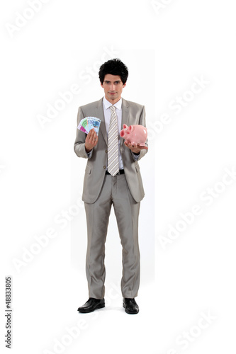 Photo: Man saving his money in a piggy bank Man saving his money in a piggy bank