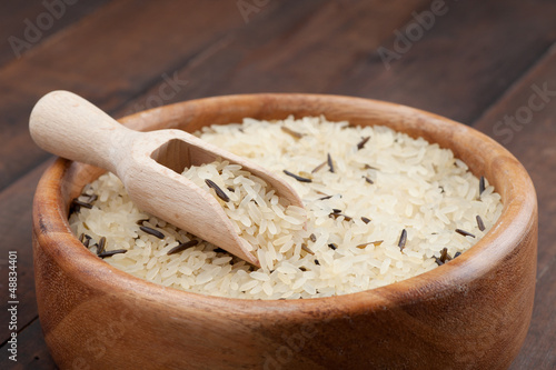 Photo: white and wild rice in wooden bowl on kitchen table white and wild rice in wooden bowl on kitchen table