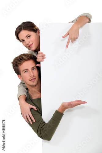 Photo: Man and woman pointing to a blank board Man and woman pointing to a blank board
