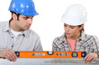 female apprentice and carpenter using ruler