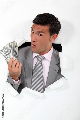 Photo: Man with banknotes of paper coming out of hole Man with banknotes of paper coming out of hole