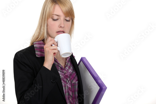 Photo: Blond worker carrying folder and coffee Blond worker carrying folder and coffee