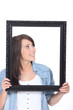 Woman stood holding empty picture frame