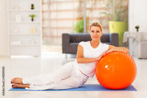 Photo: elegant middle aged sitting on mat with exercise ball elegant middle aged sitting on mat with exercise ball