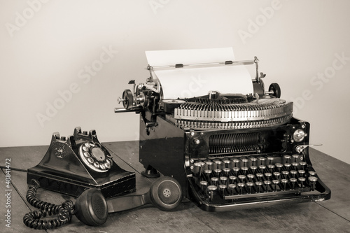 Obraz w ramie Vintage phone, old typewriter on table desaturated photo