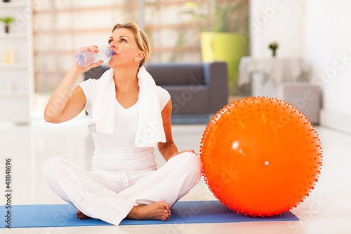 Photo: fit mature woman drinking water after exercise at home fit mature woman drinking water after exercise at home