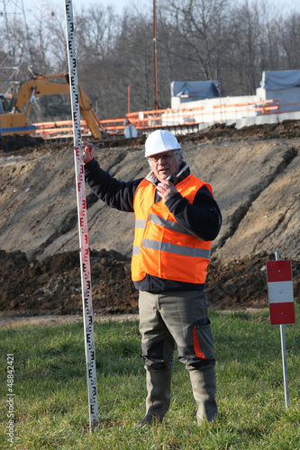 Photo: Man on construction site holding pole Man on construction site holding pole