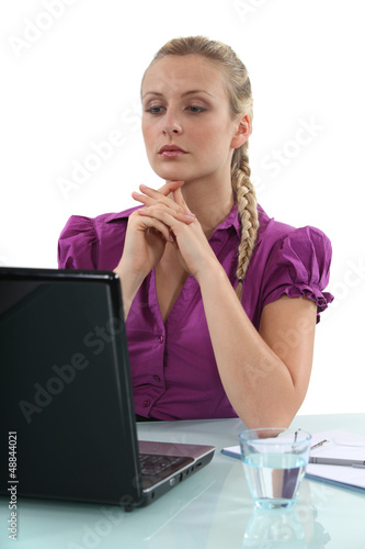 Photo: Woman sat at desk with glass of water and laptop Woman sat at desk with glass of water and laptop