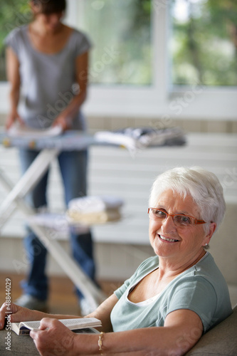 Photo: enior woman smiling and a young woman folding laundry enior woman smiling and a young woman folding laundry