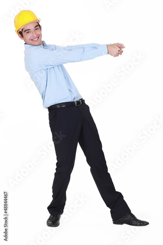 Photo: Smiling young engineer pulling an invisible rope Smiling young engineer pulling an invisible rope