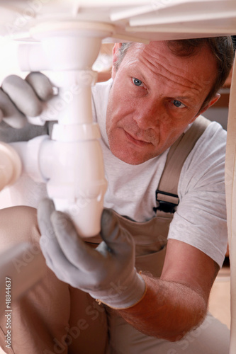 Photo: Plumber fixing a siphon Plumber fixing a siphon
