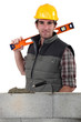 Stonemason standing before a wall and carrying a spirit level