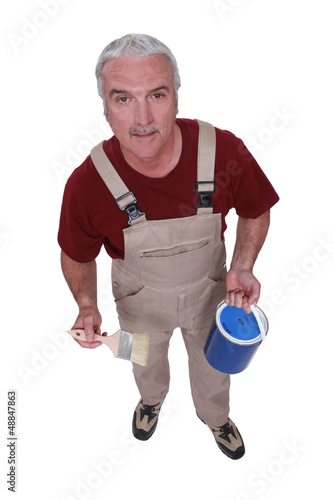 Photo: Middle-aged decorator holding paint tin and brush Middle-aged decorator holding paint tin and brush