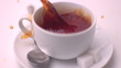 Sugar cube falling into tea and splashing