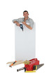 Handyman posing with a blank sign and his tools