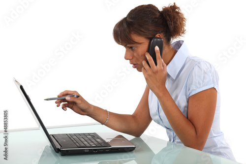 Photo: Woman on the phone in front of computer Woman on the phone in front of computer