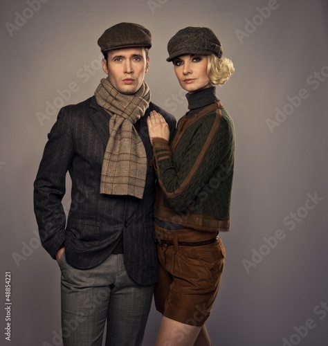 Photo: Elegant couple in caps isolated on grey background Elegant couple in caps isolated on grey background