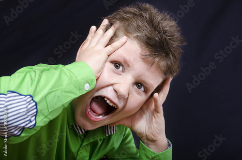 Photo: Young emotional kid on dark fabric background Young emotional kid on dark fabric background