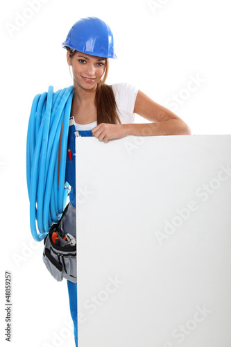 Photo: Female electrician stood by advertising panel Female electrician stood by advertising panel