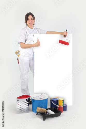 Photo: Painter posing with her supplies next to a blank sign Painter posing with her supplies next to a blank sign