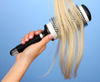 Blond curls brushing comb on color background