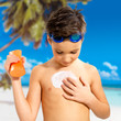 boy applying sun block cream on the tanned body