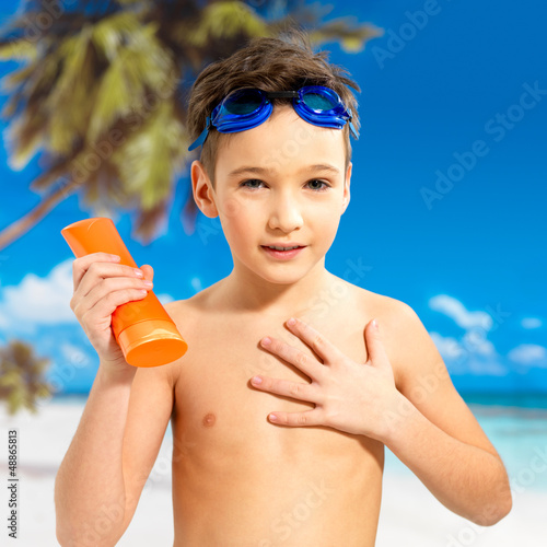 Photo: boy applying sun block cream on the tanned body boy applying sun block cream on the tanned body