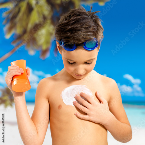 Photo: boy applying sun block cream on the tanned body boy applying sun block cream on the tanned body