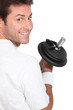 Smiling man looking over his shoulder holding dumbbell