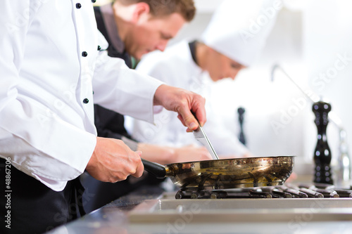 Photo: Three chefs in team in hotel or restaurant kitchen Three chefs in team in hotel or restaurant kitchen