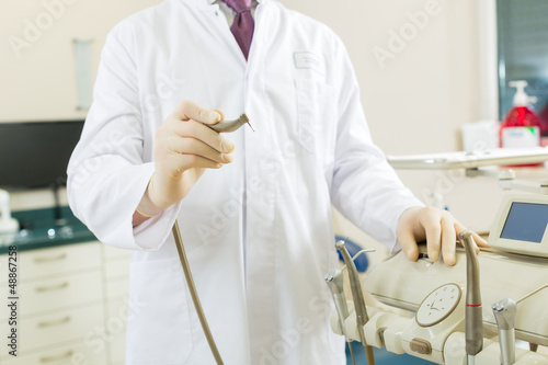 Photo: Dentist in his surgery, he holds a drill Dentist in his surgery, he holds a drill