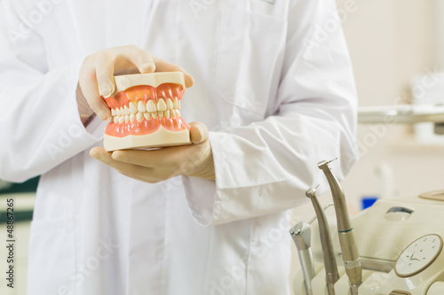Photo: Dentist in his surgery, he holds a denture Dentist in his surgery, he holds a denture