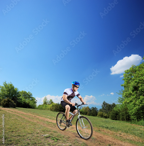 Photo: Male bicyclist riding a mountain bike downhill Male bicyclist riding a mountain bike downhill