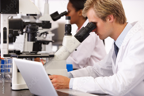 Photo: Male And Female Scientists Using Microscopes In Laboratory Male And Female Scientists Using Microscopes In Laboratory